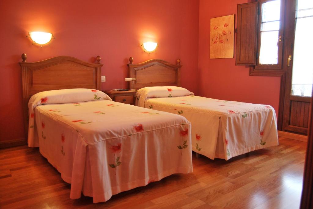 two beds in a room with red walls and wooden floors at La Becada de Buelna in Los Corrales de Buelna