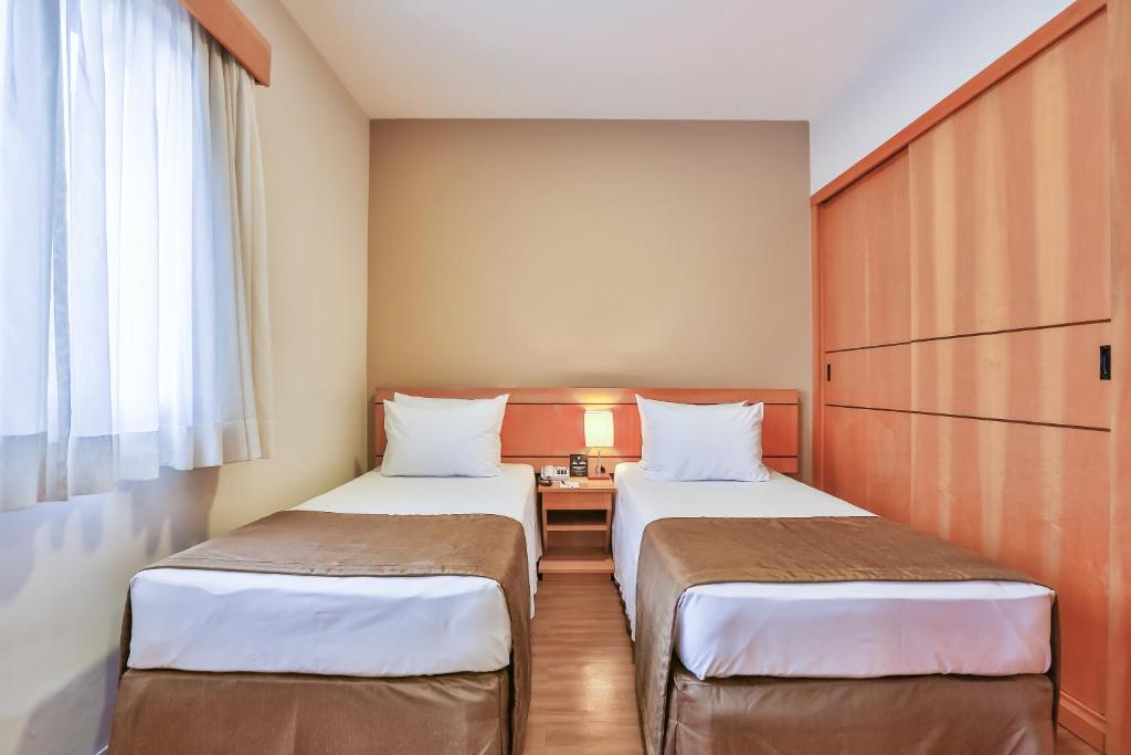 um quarto de hotel com duas camas e uma janela em Hampton Park São Paulo Jardins em São Paulo