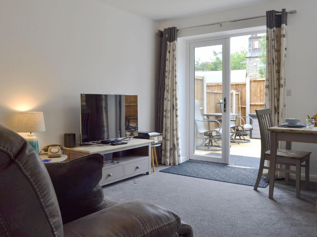 a living room with a couch and a television and a table at Shepley Mews in Glossop