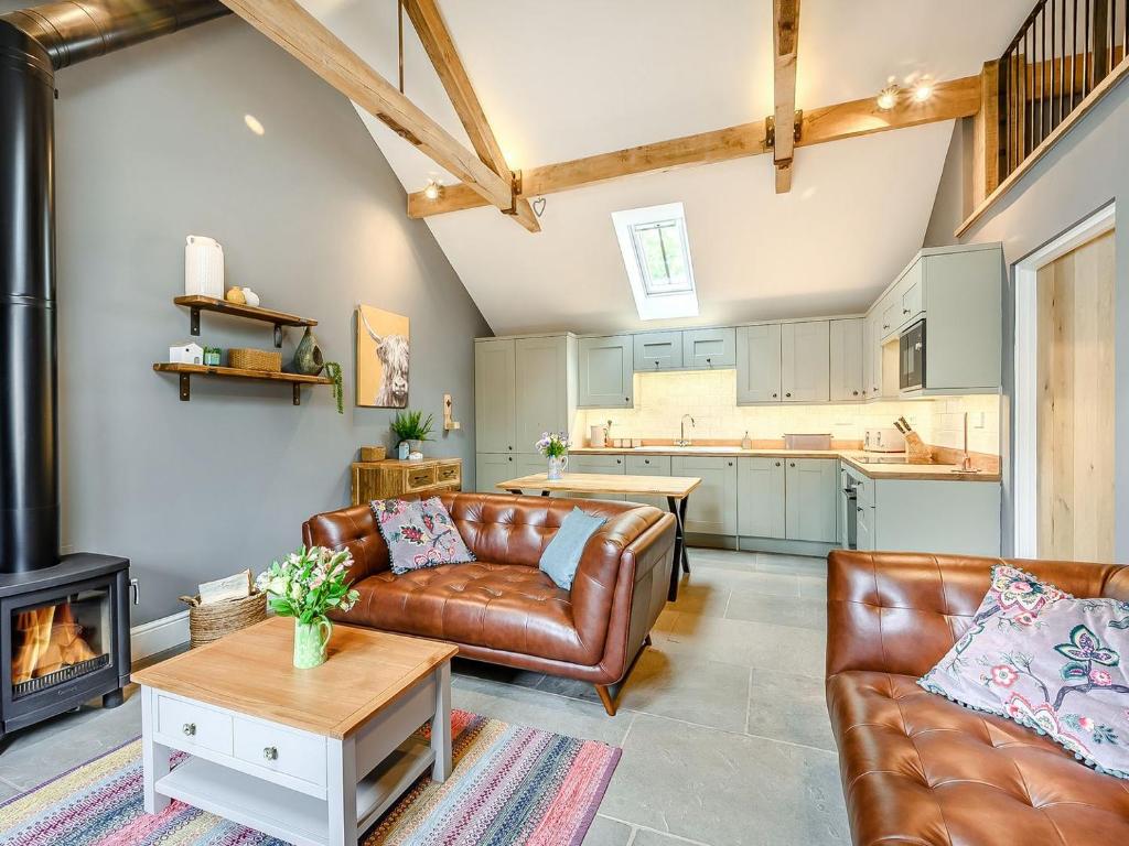 sala de estar con sofá de cuero y chimenea en The Cow Shed - Uk38575, en Aston Cantlow