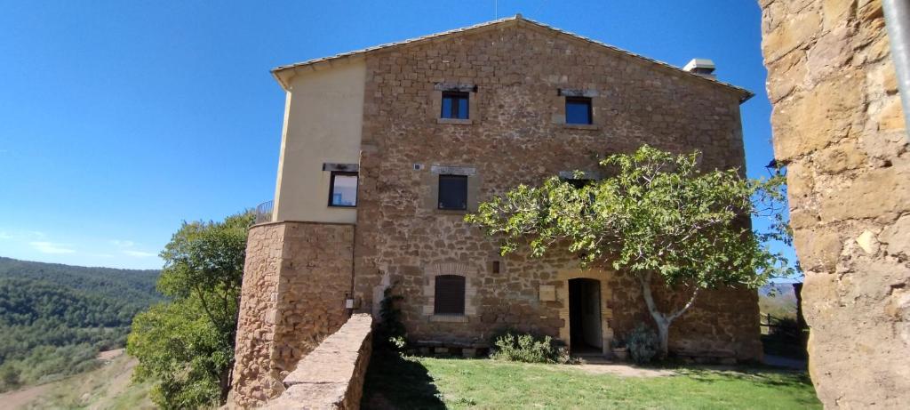 un viejo edificio de piedra con un árbol delante de él en Castell de Ceuró. Hotel Rural, en 