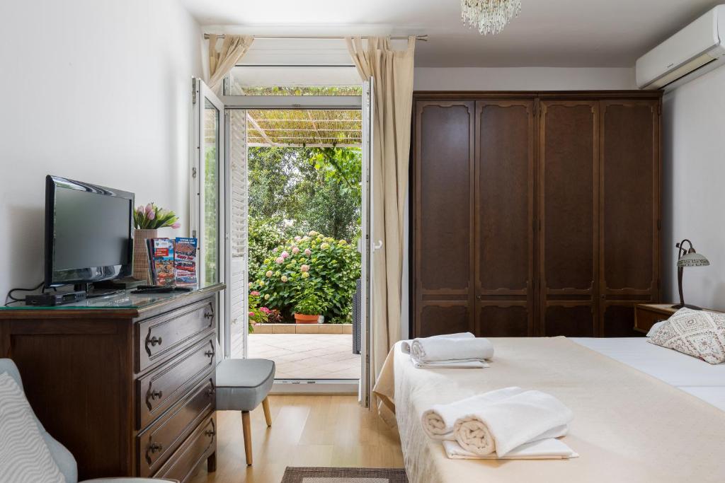 ein Schlafzimmer mit einem Bett, einem TV und einer Glasschiebetür in der Unterkunft Studio and Room Lena in Dubrovnik