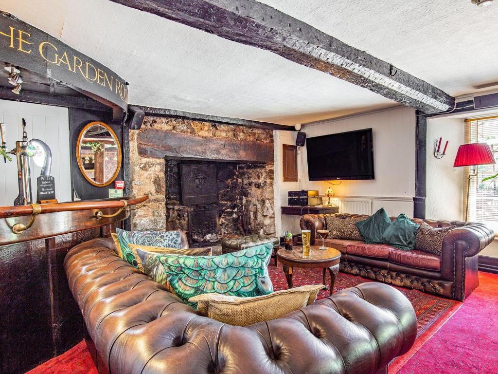 a living room with a leather couch and a fireplace at Old Rydon Inn in Kingsteignton