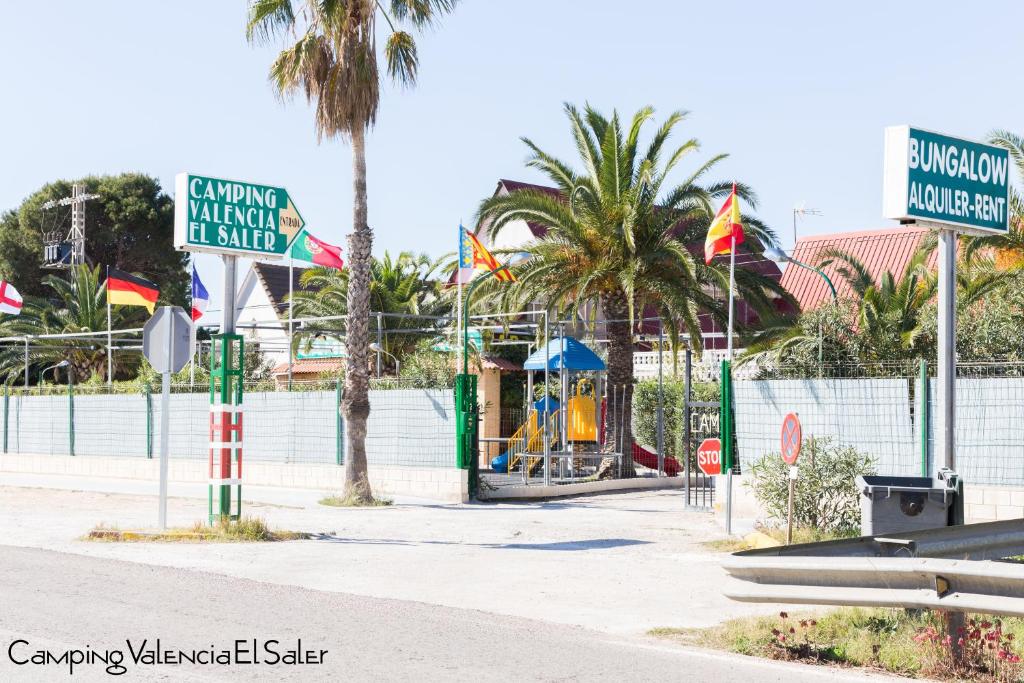 a park with a playground with palm trees and signs at Camping Valencia el Saler in El Saler