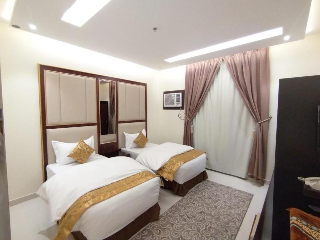 ein Hotelzimmer mit 2 Betten und einem Fenster in der Unterkunft الشرق بارك للشقق المخدومة in Al Mikhlaf