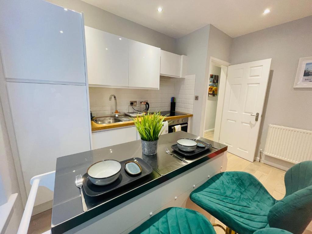 a kitchen with a counter and some green chairs at Bristol City Stays - Harbourside Apartments in Bristol