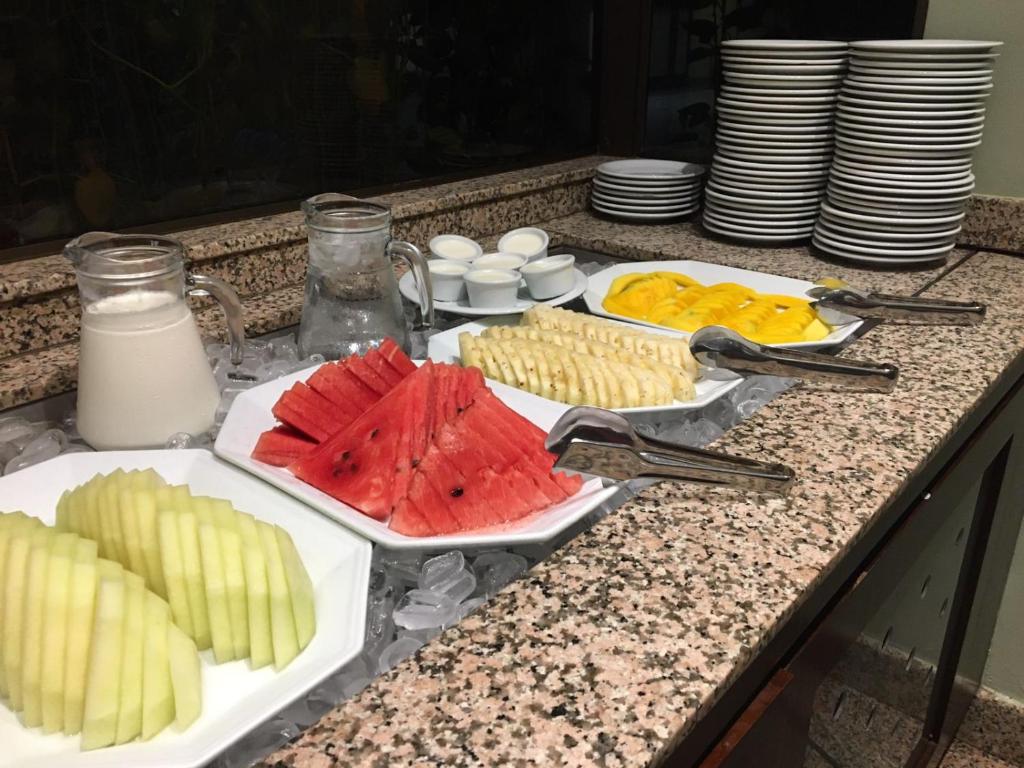 a table topped with plates of fruit and milk at Pousada dos Girassóis in Palmas