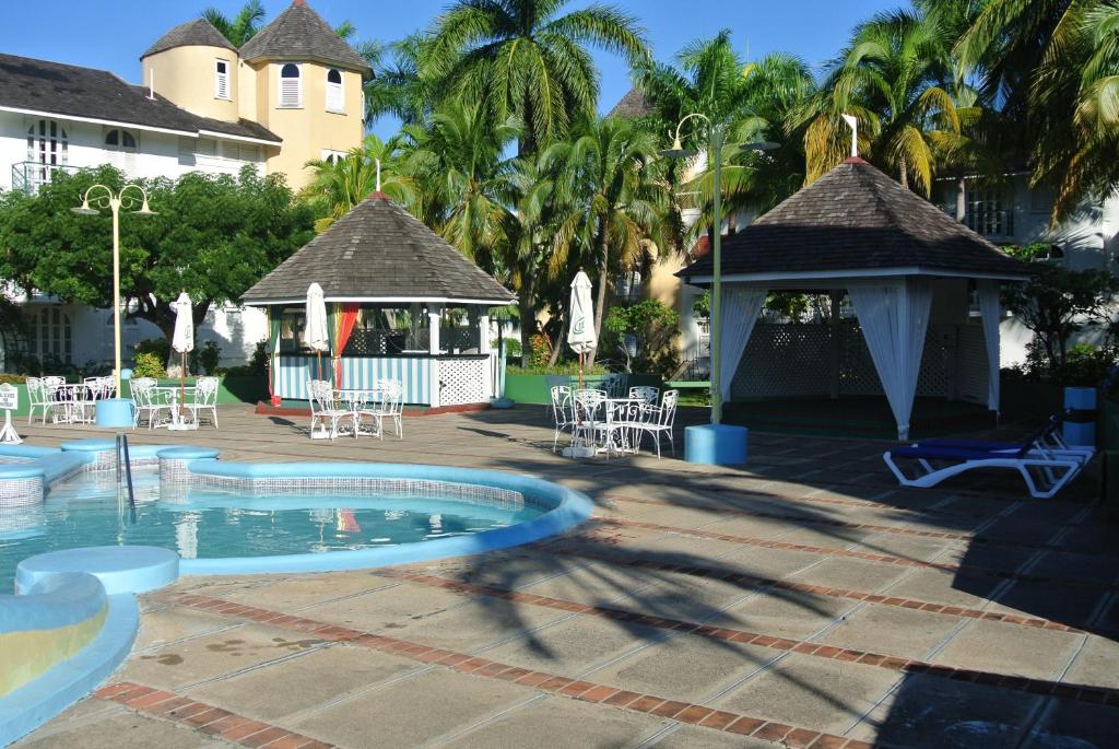 einen Pool in einem Resort mit einem Pavillon und Palmen in der Unterkunft Beach Studio 9 in Ocho Rios