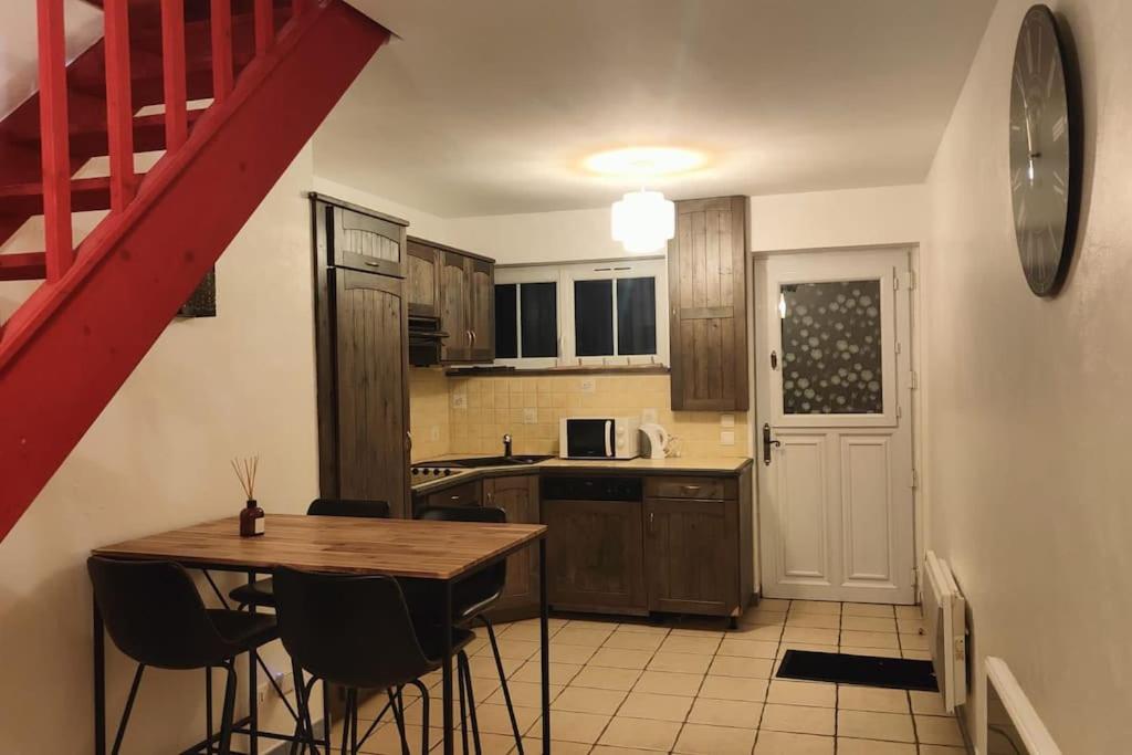 eine Küche mit einem Holztisch und einer roten Treppe in der Unterkunft Charmante maison de ville in Bolbec