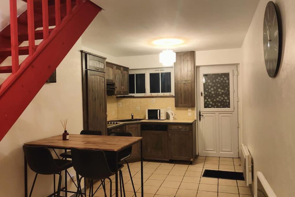 a kitchen with a wooden table and a red staircase at Charmante maison de ville in Bolbec