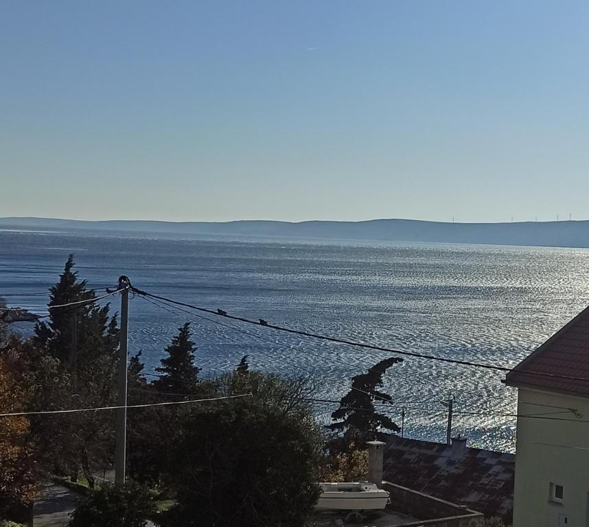 einen Blick auf das Meer mit Vögeln auf einem Draht in der Unterkunft Apartments Happy Day in Karlobag