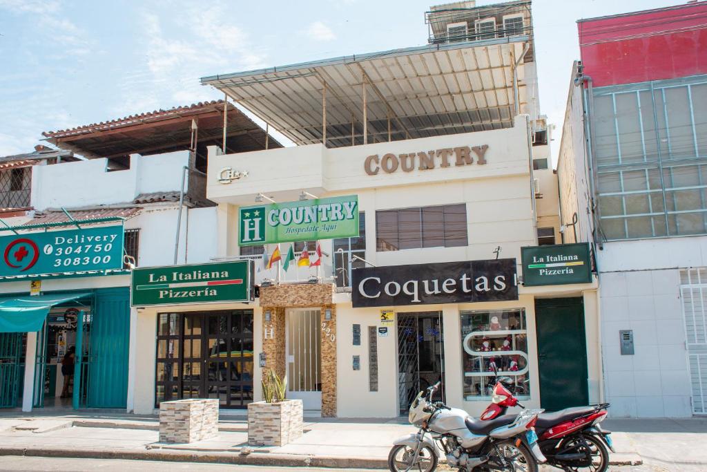 a motorcycle parked in front of a building with shops at Hotel Country Boutique in Piura