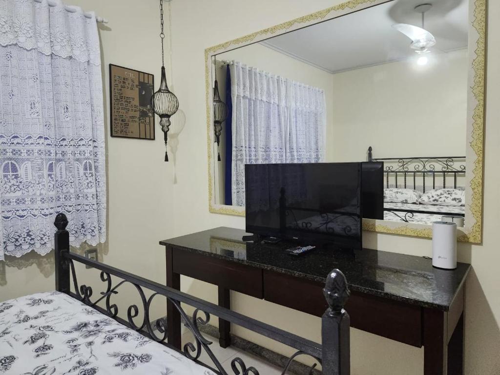1 dormitorio con espejo y escritorio con TV en Pousada mais confortável de Itapema, en Itapema