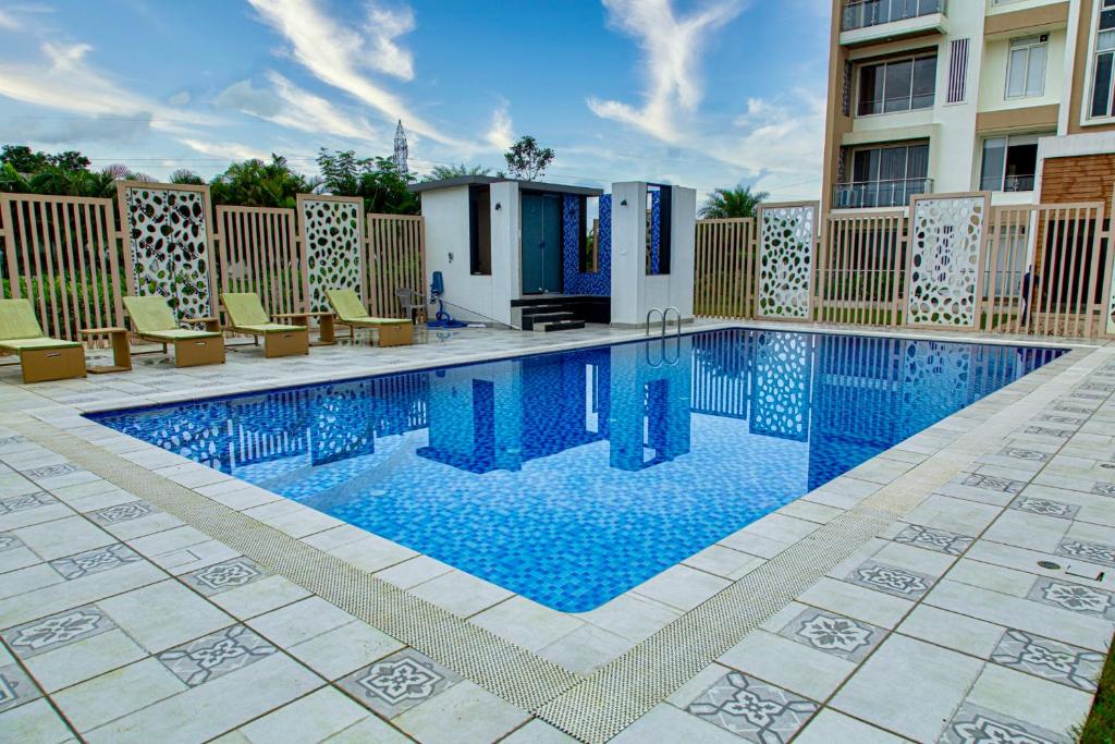 a swimming pool with chairs and a building at CAPETOWN VILLAS (MOUNTAIN VIEW) in Igatpuri