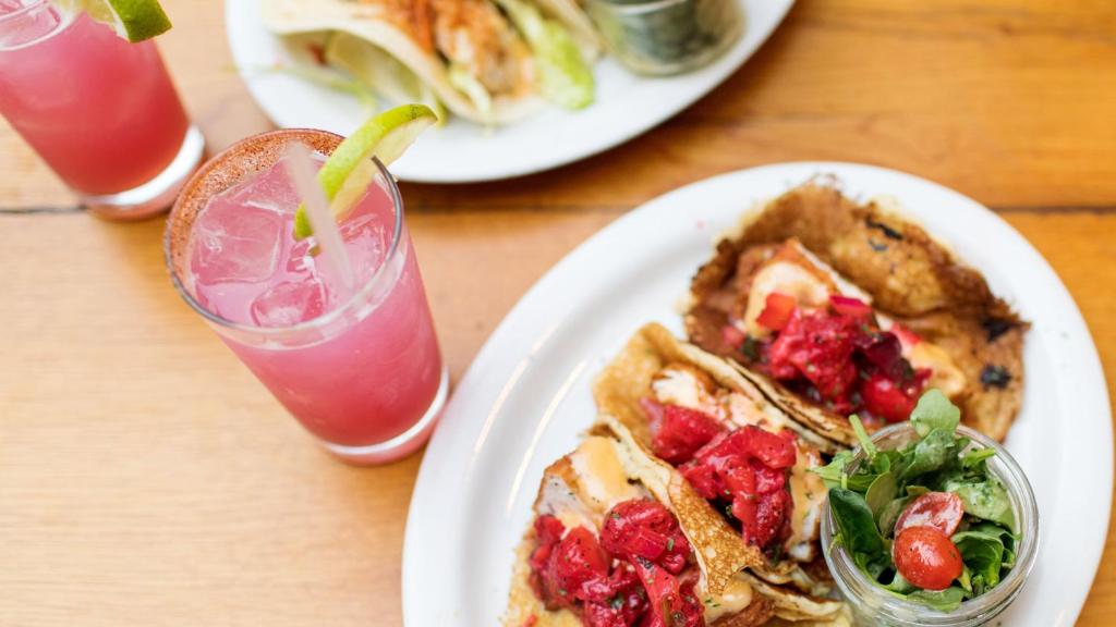 a table with two plates of food and a drink at Hotel Indigo Orange Beach - Gulf Shores by IHG in Gulf Shores