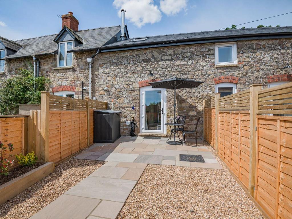 a stone house with a wooden fence and a patio at The Hayloft - Uk40092 in Bryngwyn