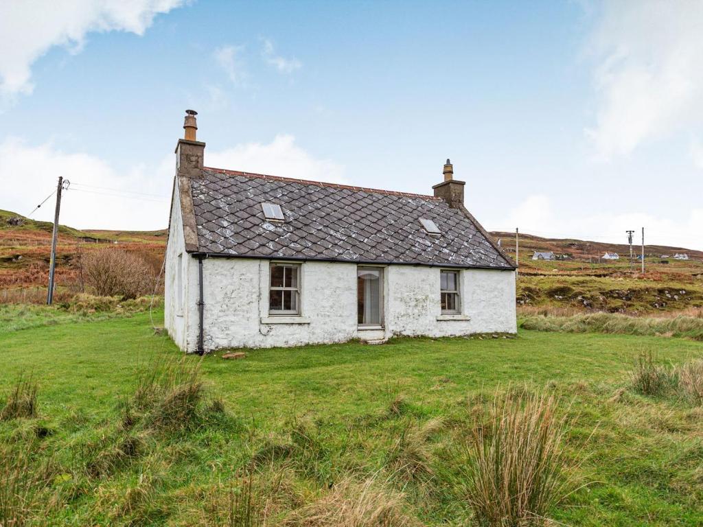 an old white cottage in a field of grass at Herons Rest in Glendale