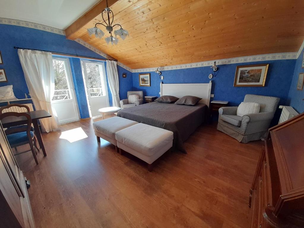 ein Schlafzimmer mit blauen Wänden und einem Bett und einem Sofa in der Unterkunft La maison de Maria in Saint-Beauzire