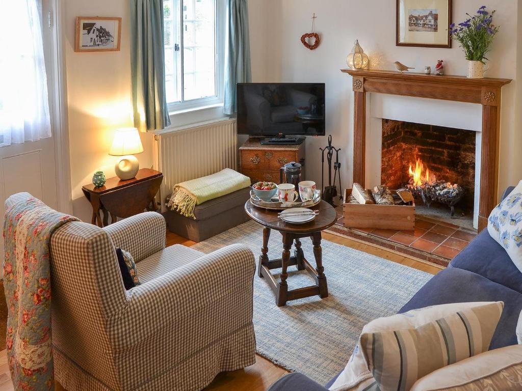 a living room with a couch and a fireplace at Lavenham Red Brick Cottage in Lavenham