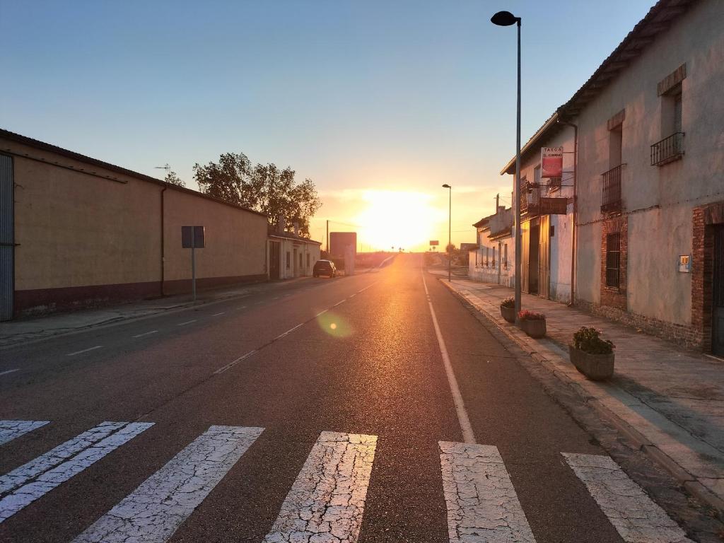 an empty street with the sun setting in the distance at Don Camino in Villalcázar de Sirga