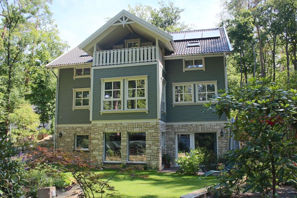 a house with green paint and trees at Moderne Wohnung im skandinavischen Stil am Waldrand in Schwielowsee