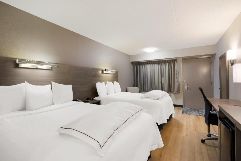 Habitación de hotel con 2 camas con sábanas blancas en Red Roof Inn PLUS+ Chicago - Naperville en Naperville