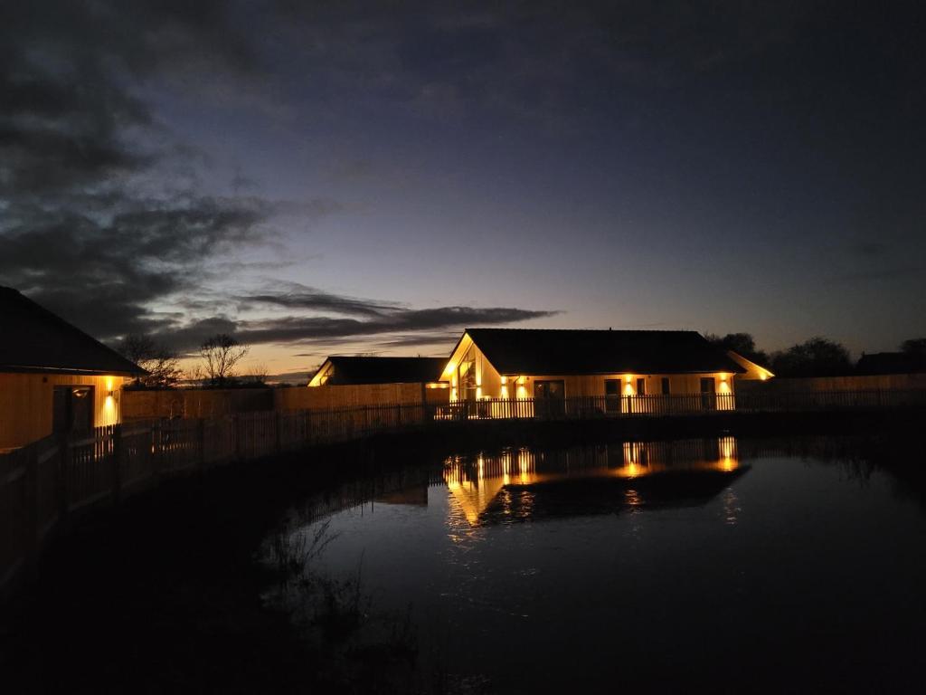 una casa con luces en el agua por la noche en Mallard Cottage, Ashlin Farm Barns en Lincoln