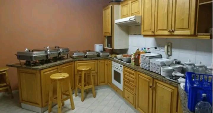 a kitchen with wooden cabinets and a counter with stools at Palm View Apartment in Pretoria
