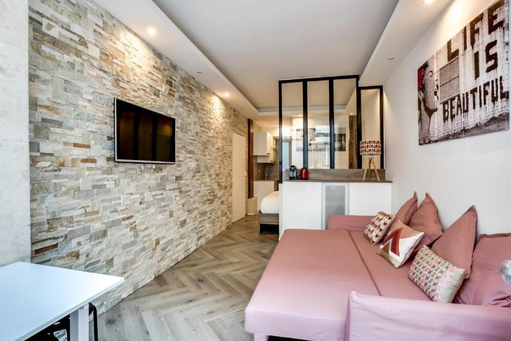 - un salon avec un canapé rose et un mur en briques dans l'établissement Comfortable apartment - 1BR-4P - Palais Garnier, à Paris