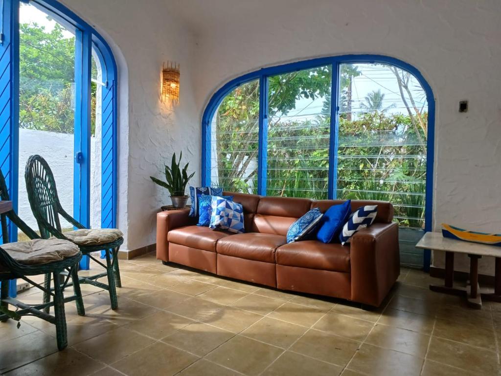 a brown leather couch in a room with large windows at Casa com Spa Praia do Pernambuco in Guarujá
