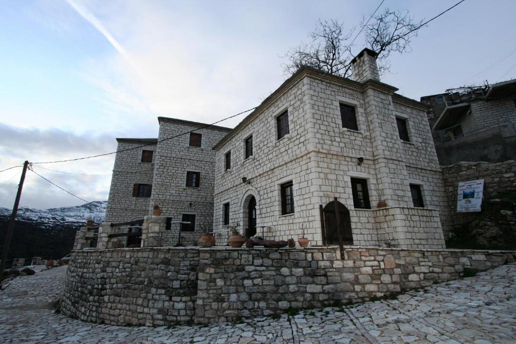 un antiguo edificio de piedra en una pared de piedra en Petradi 1873, en Kalarites