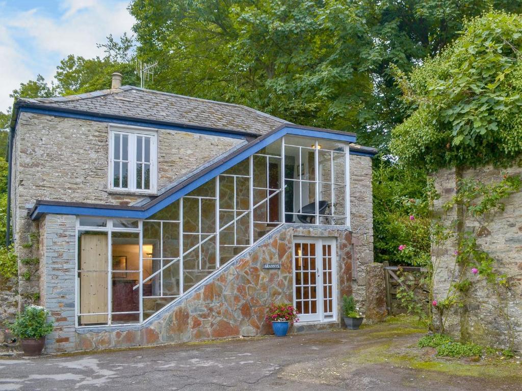 une maison en pierre avec une grande fenêtre dans l'établissement Grannys Cottage, à Lostwithiel
