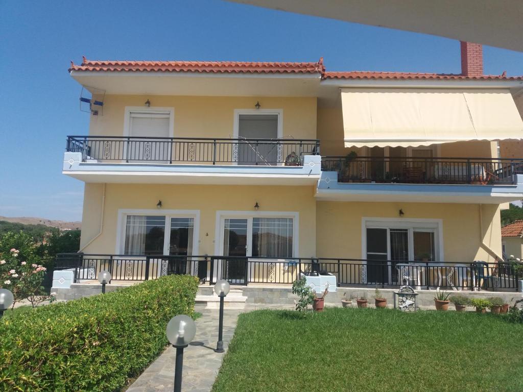 a large yellow house with a balcony at Irini's Appartment 2 in Néa Koútali