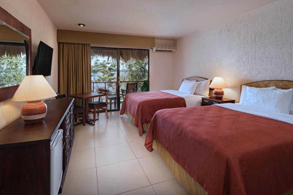 ein Hotelzimmer mit 2 Betten, einem Tisch und Stühlen in der Unterkunft Camino Real Tikal‎ in El Remate