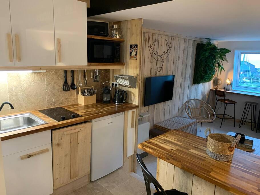 a kitchen with a wooden counter top and a table at NOUVEAU Charme et vue mer in Deauville