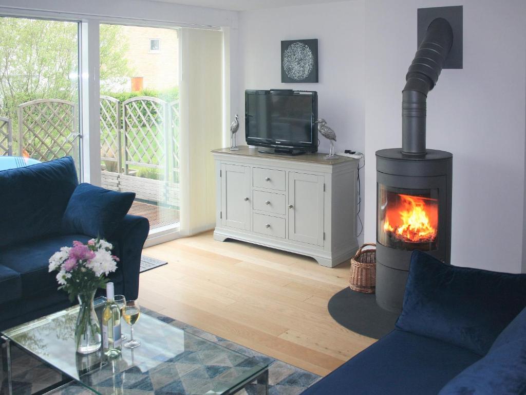 a living room with a fireplace and a tv at Chestnut Lodge in Somerford Keynes