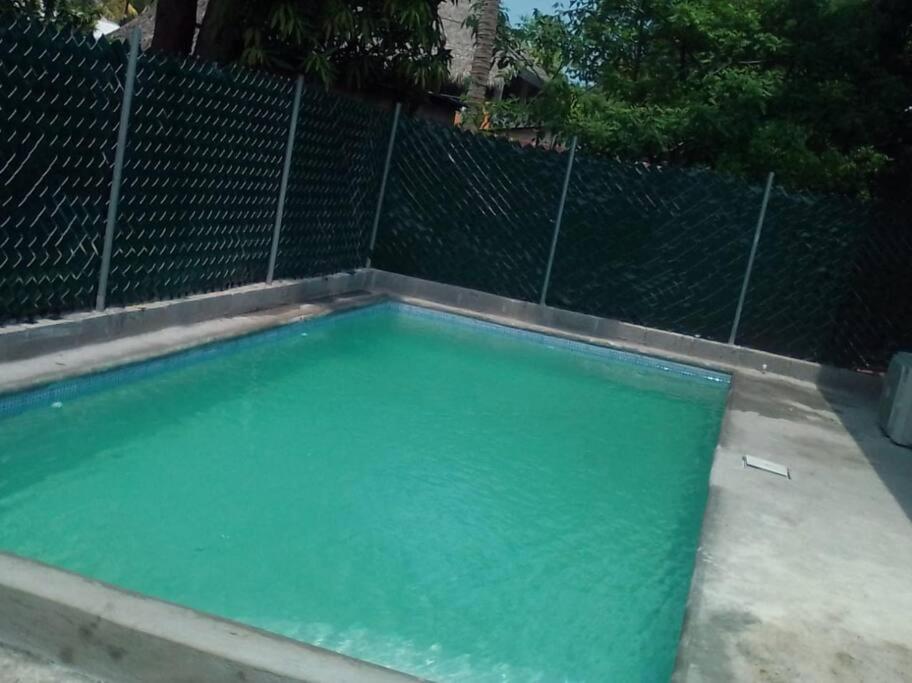 a swimming pool with green water in front of a fence at El Chalet del Canche in Iztapa