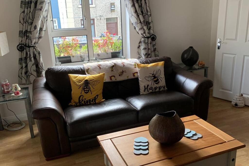 un sofá de cuero en una sala de estar con mesa de centro en Bumblebee Cottage, en Donegal