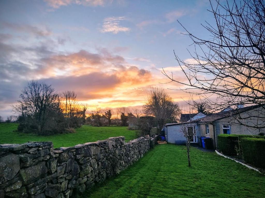 a field with a stone wall and a building at Annie Dee’s Guest Accommodation in Ballygowan