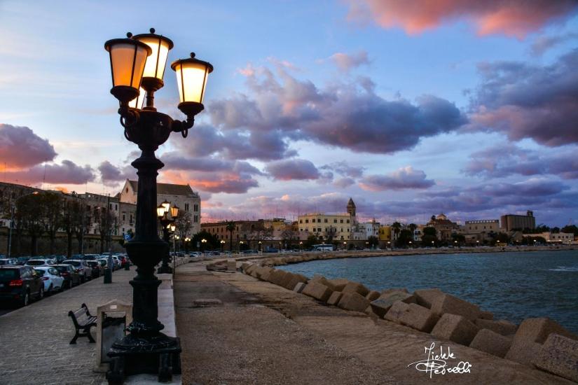 a street light on a sidewalk next to a body of water at hotel de rossi in Bari