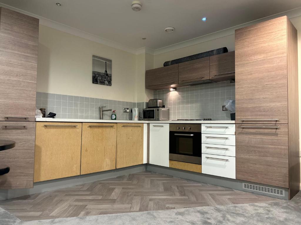 uma cozinha com armários de madeira e electrodomésticos brancos em 2 bedroom apartment city centre Birmingham em Birmingham