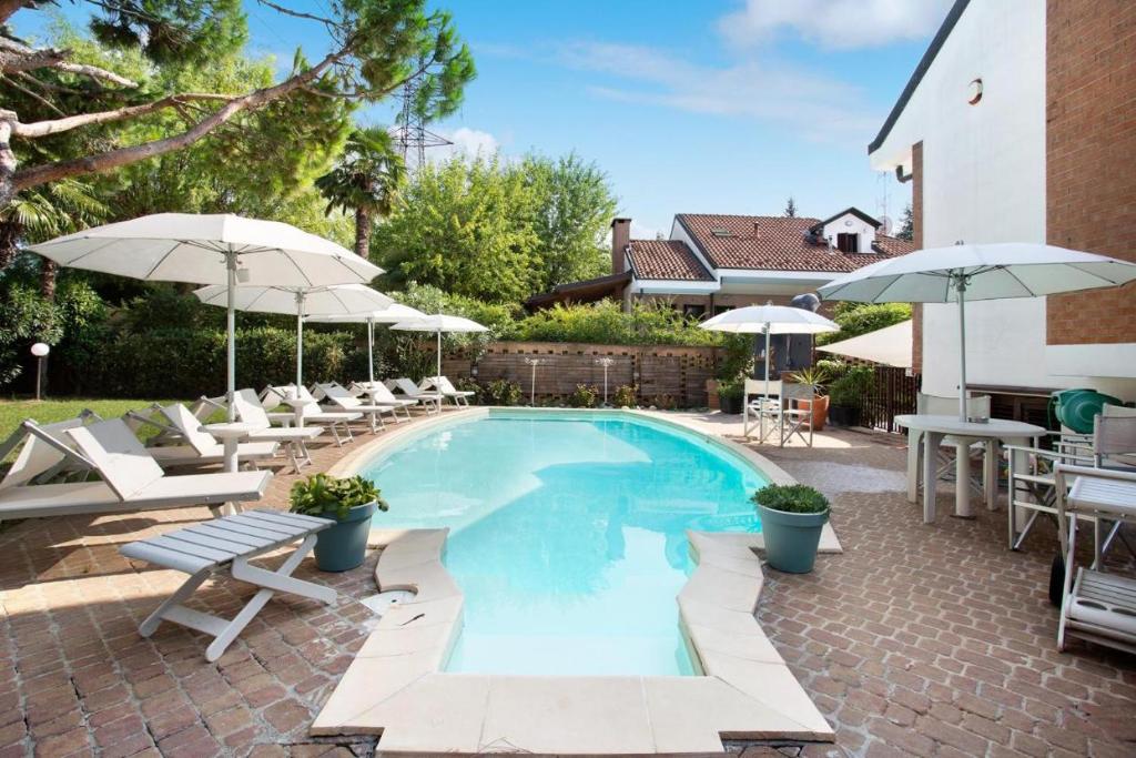 a swimming pool with chairs and umbrellas at Villa La palmetta in Peschiera Borromeo