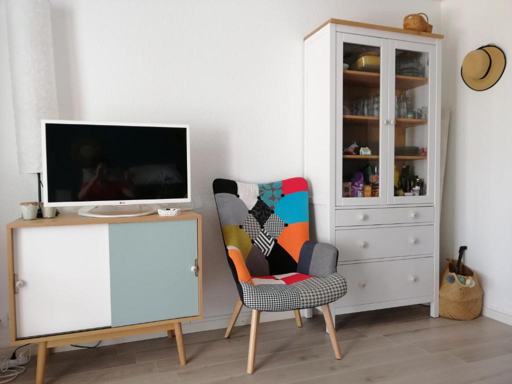 uma sala de estar com uma televisão e uma cadeira em Charmant T2 avec grande terrasse et confort 3 étoiles em La Grande-Motte