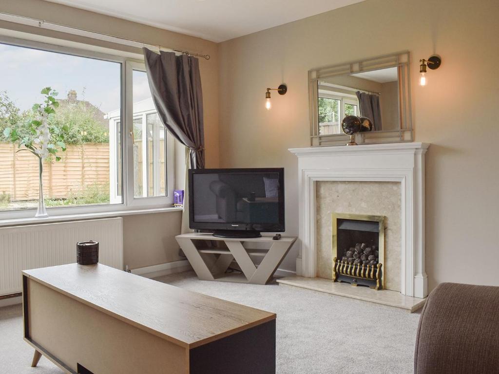 a living room with a tv and a fireplace at Ewe Cottage in Ashbourne