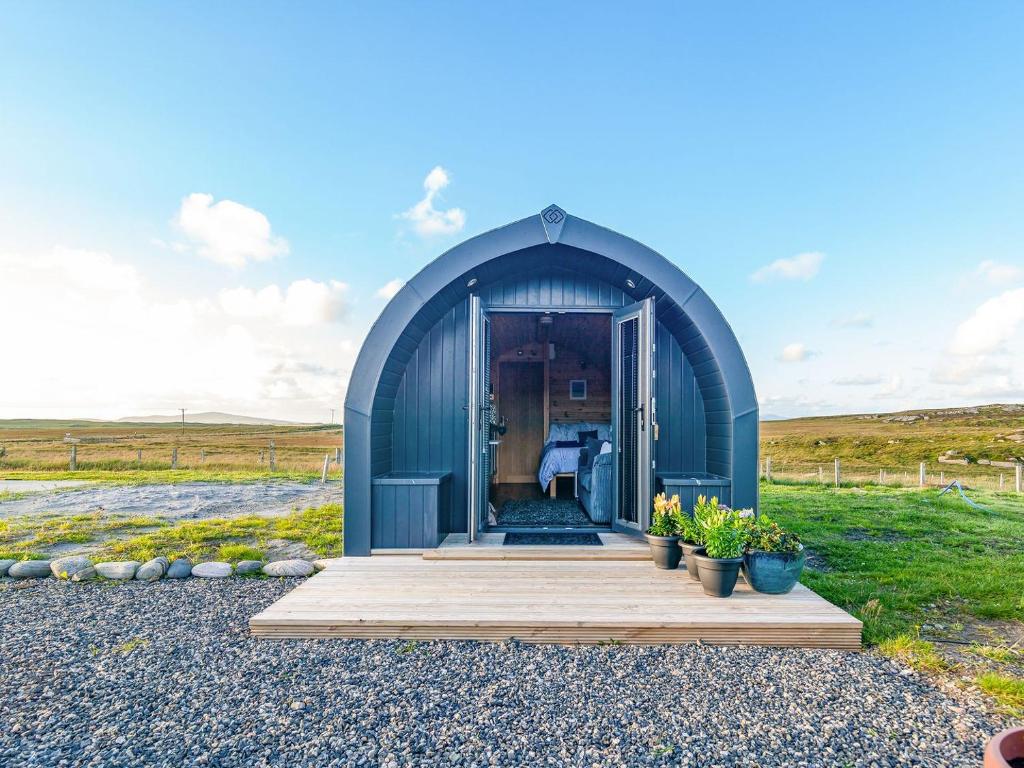 a blue shed with a wooden porch in a field at Boreray - Uk40644 in Trumisgarry