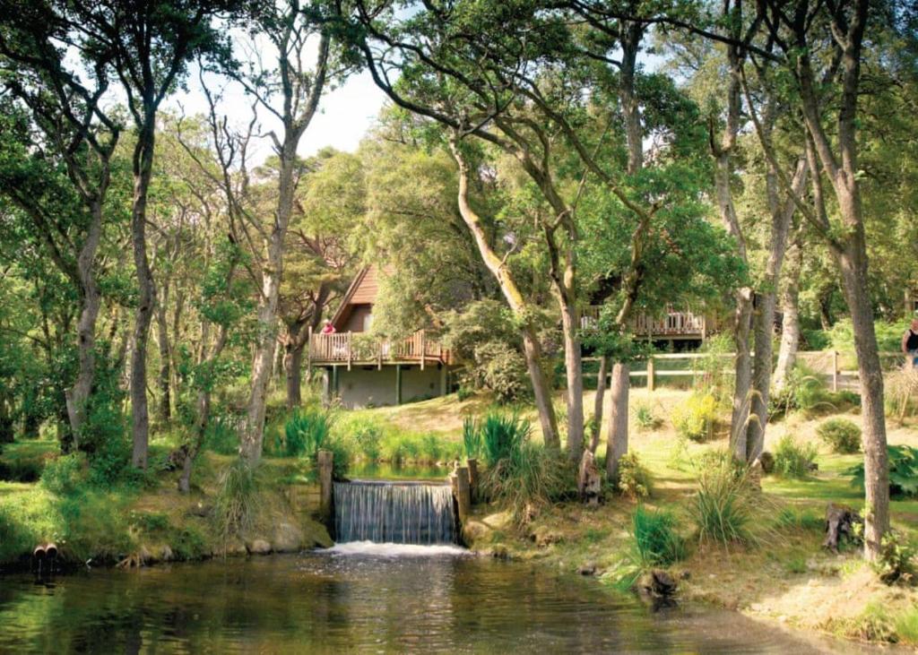 a house next to a river with a waterfall at Delny Highland Lodges in Invergordon