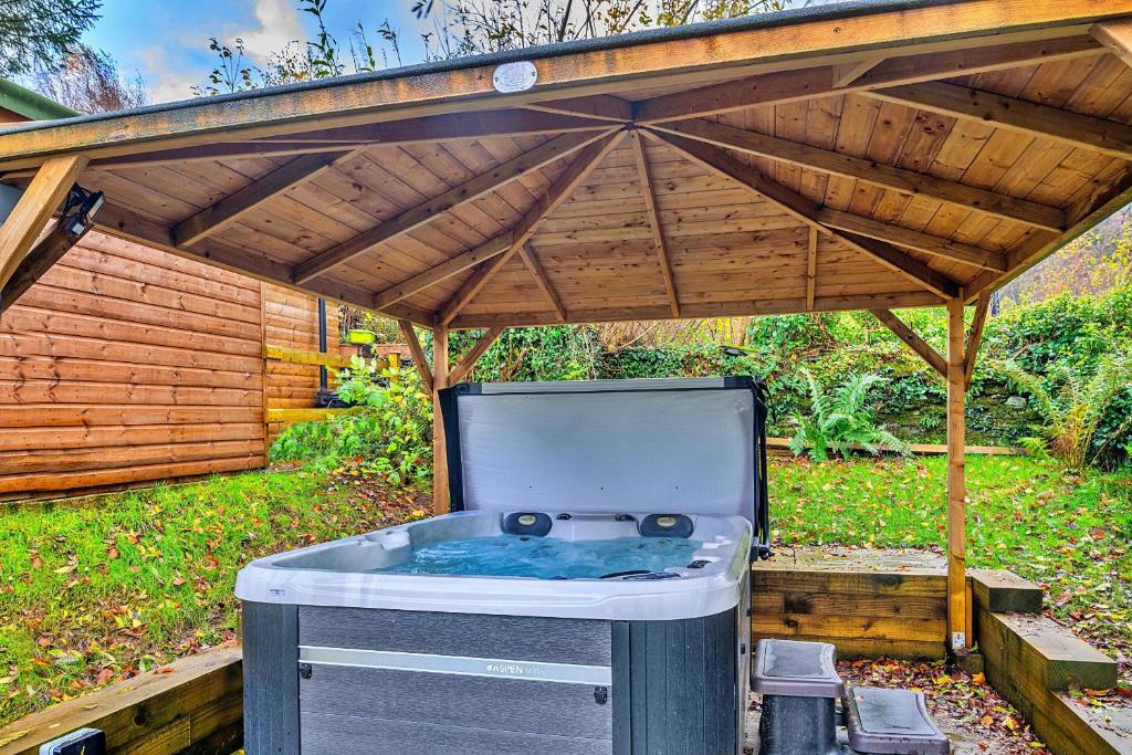 a hot tub under a wooden pergola at Finest Retreats - Harp House in Dolwyddelan