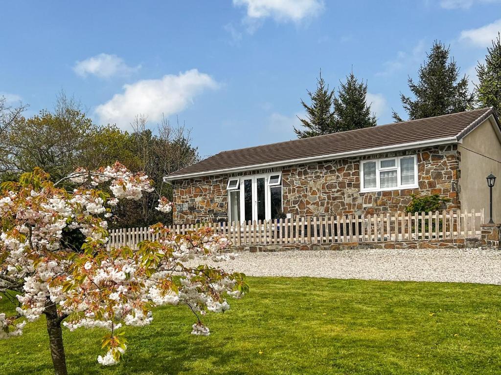 a stone house with a fence and a tree at Swallows Rest in Doublebois