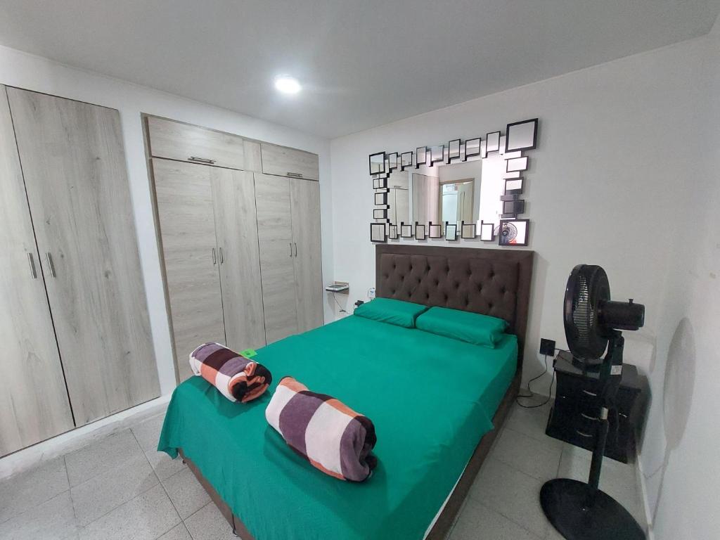 a bedroom with a green bed and a mirror at VITAL- APARTAMENTO Sector san alonso in Bucaramanga