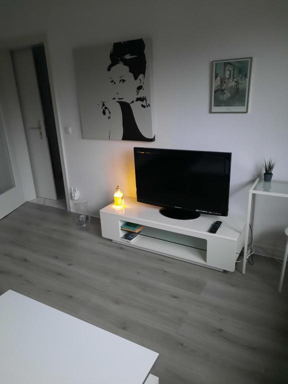 sala de estar con TV de pantalla plana en un centro de entretenimiento blanco en Happy Living, en Mülheim an der Ruhr